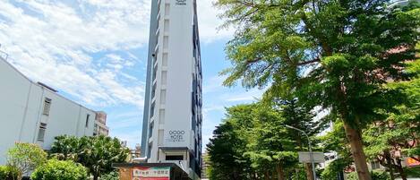 A tall hotel building with a modern design, a visible sign for the Gogo Hotel, and a parking area with motorcycles and cars.
