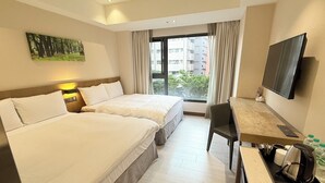 A hotel room with two beds, a desk, a TV, and a window with a view of buildings. - Icasa By GoGo Hotel (Taichung)