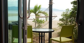 Una habitación con vista a la playa, una hamaca y dos sillas amarillas.