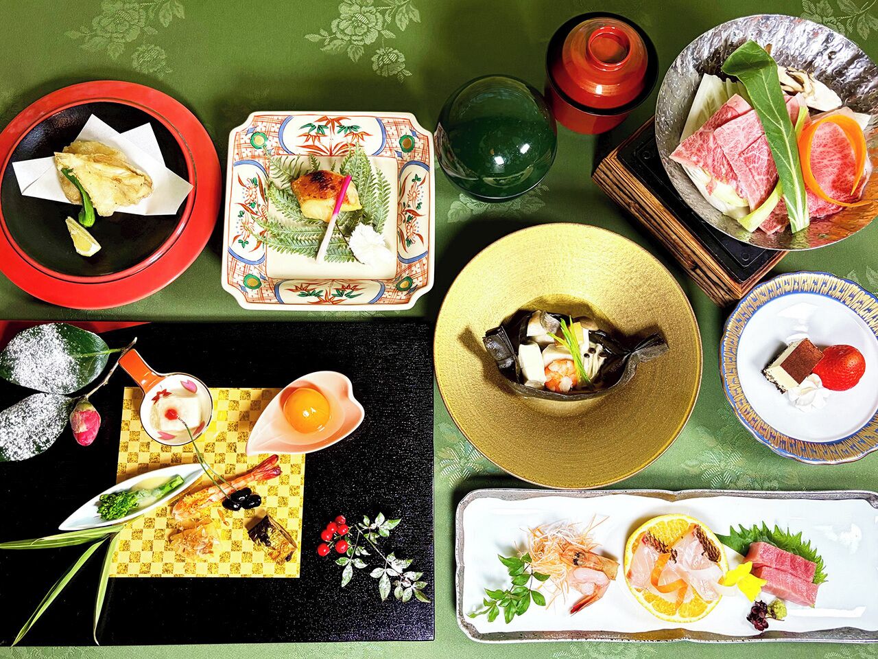 A table set with various dishes, including sushi, sashimi, and a dessert.