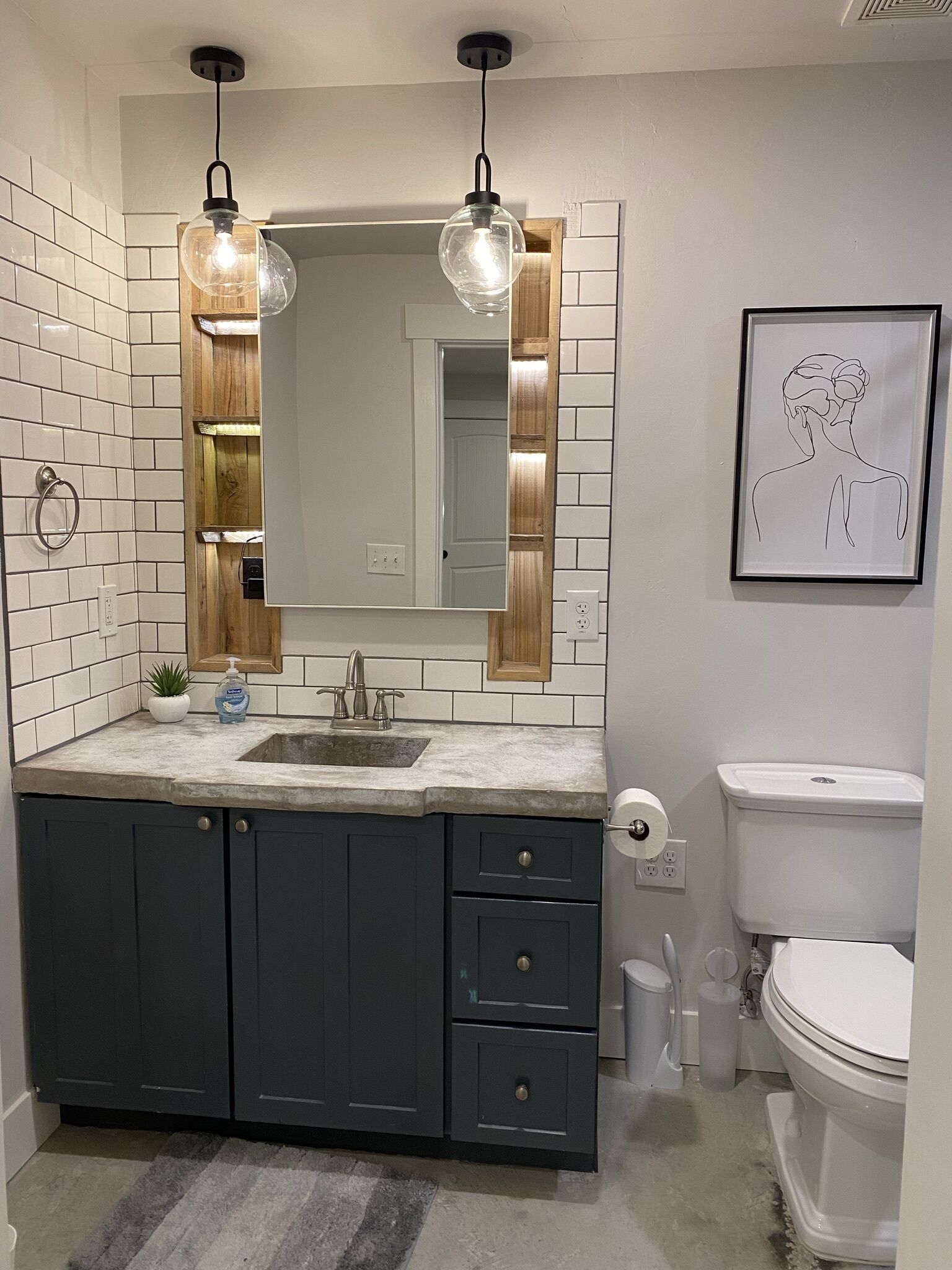 Une salle de bain moderne avec un grand miroir, des meubles sombres, un lavabo et des toilettes.