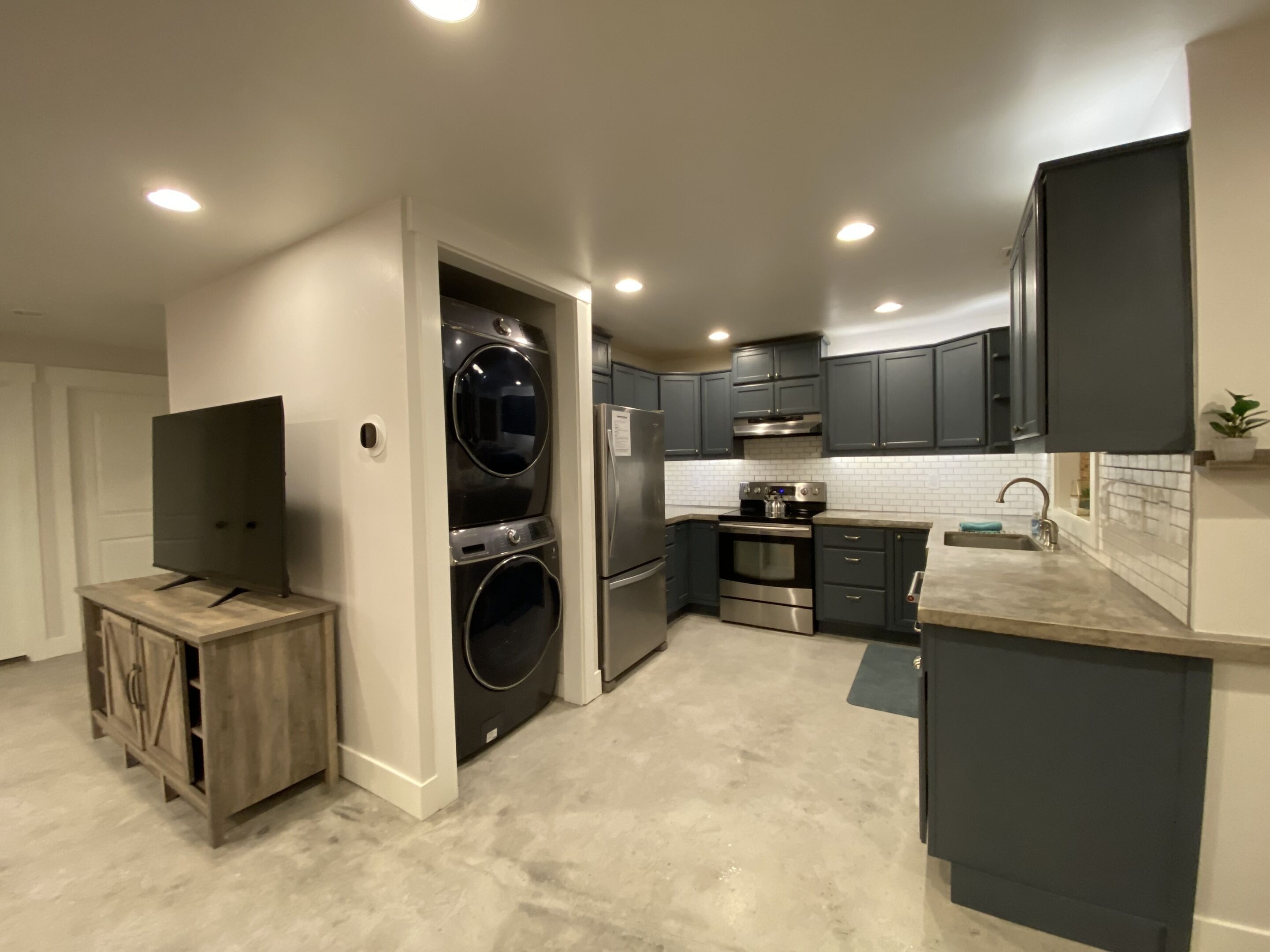 A modern kitchen with dark cabinets, stainless steel appliances, and a built-in washer and dryer.