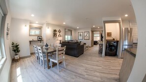 A spacious living area with a dining table, chairs, a sofa, and a washing machine. - The Raspberry Garden Luxury Hotel & Suites (Rexburg)