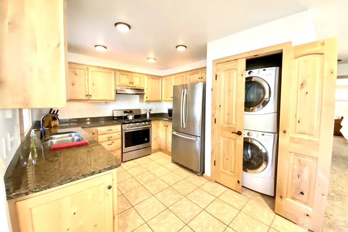 A kitchen with wooden cabinets, stainless steel appliances, a built-in oven, a refrigerator, and a washing machine.