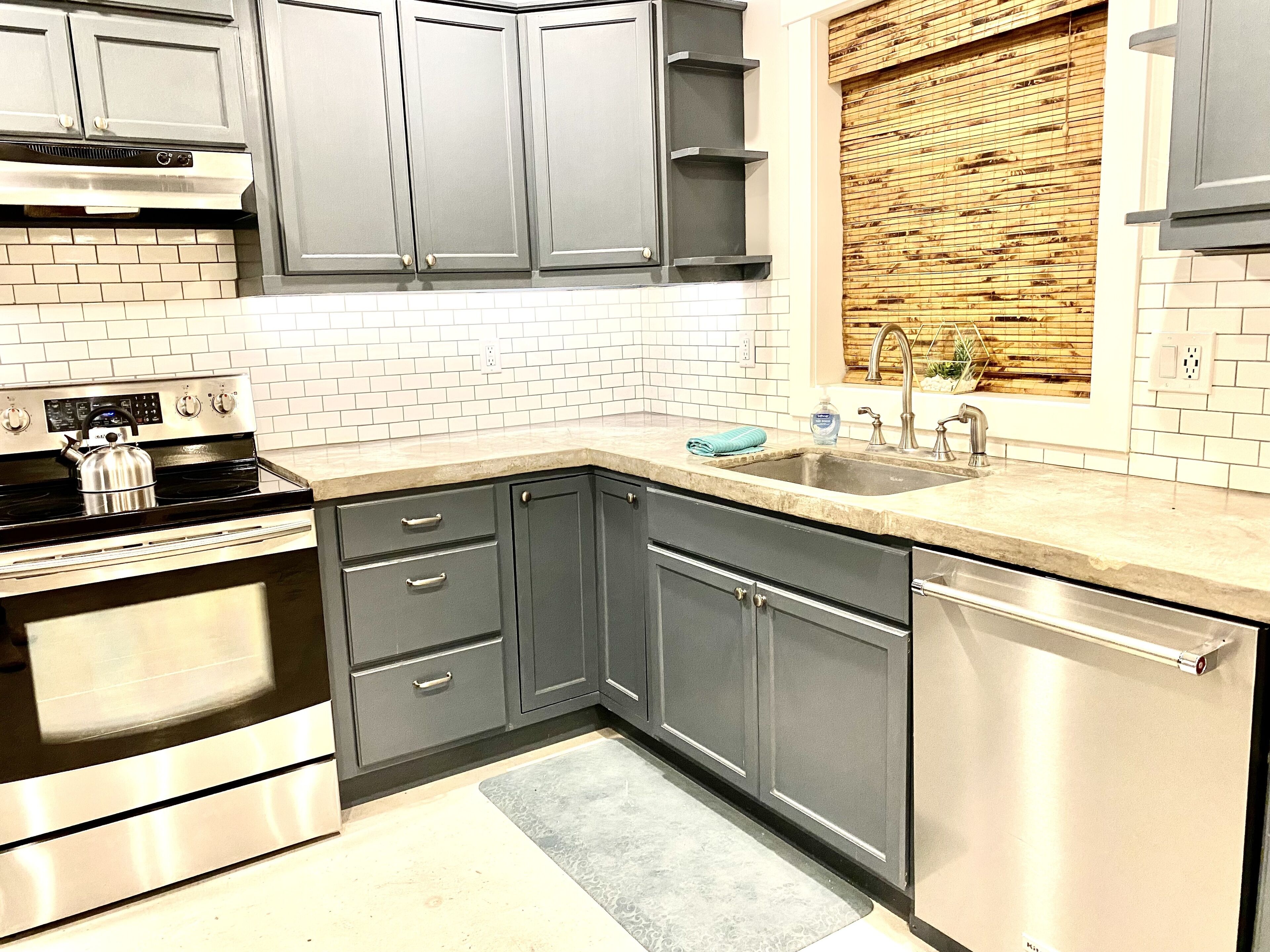 A modern kitchen with grey cabinets, a stainless steel stove, and a sink.