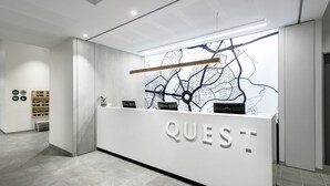 A modern reception desk with a map mural, a 'QUEST' sign, and a minimalist design. - Quest Canberra City Walk (Canberra)