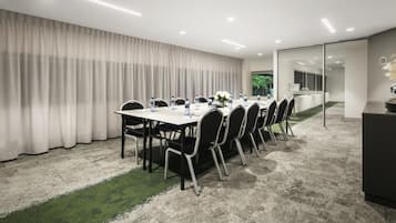 A conference room with a long table, chairs, and a carpeted floor.