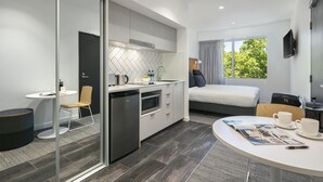 A modern hotel room with a kitchen, a dining area, and a bed. - Quest Canberra City Walk (Canberra)