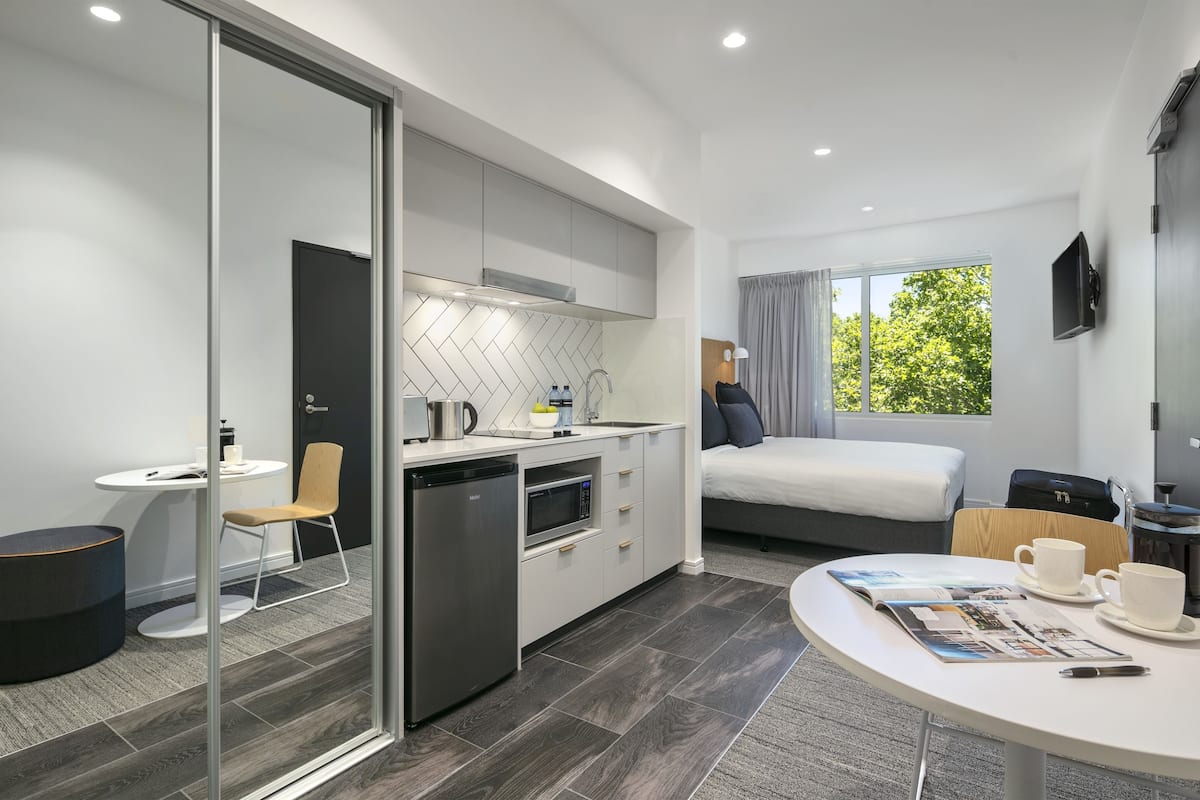 Una habitación de hotel moderna con cocina, comedor y cama.
