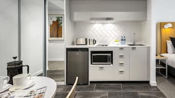 A compact kitchen with a microwave, toaster, and coffee maker, a dishwasher, and a herringbone-patterned backsplash.