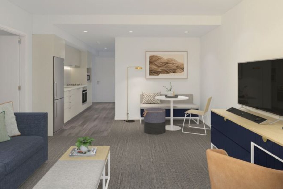 A modern living room with a sofa, coffee table, TV, and a small dining area with a table and chairs.