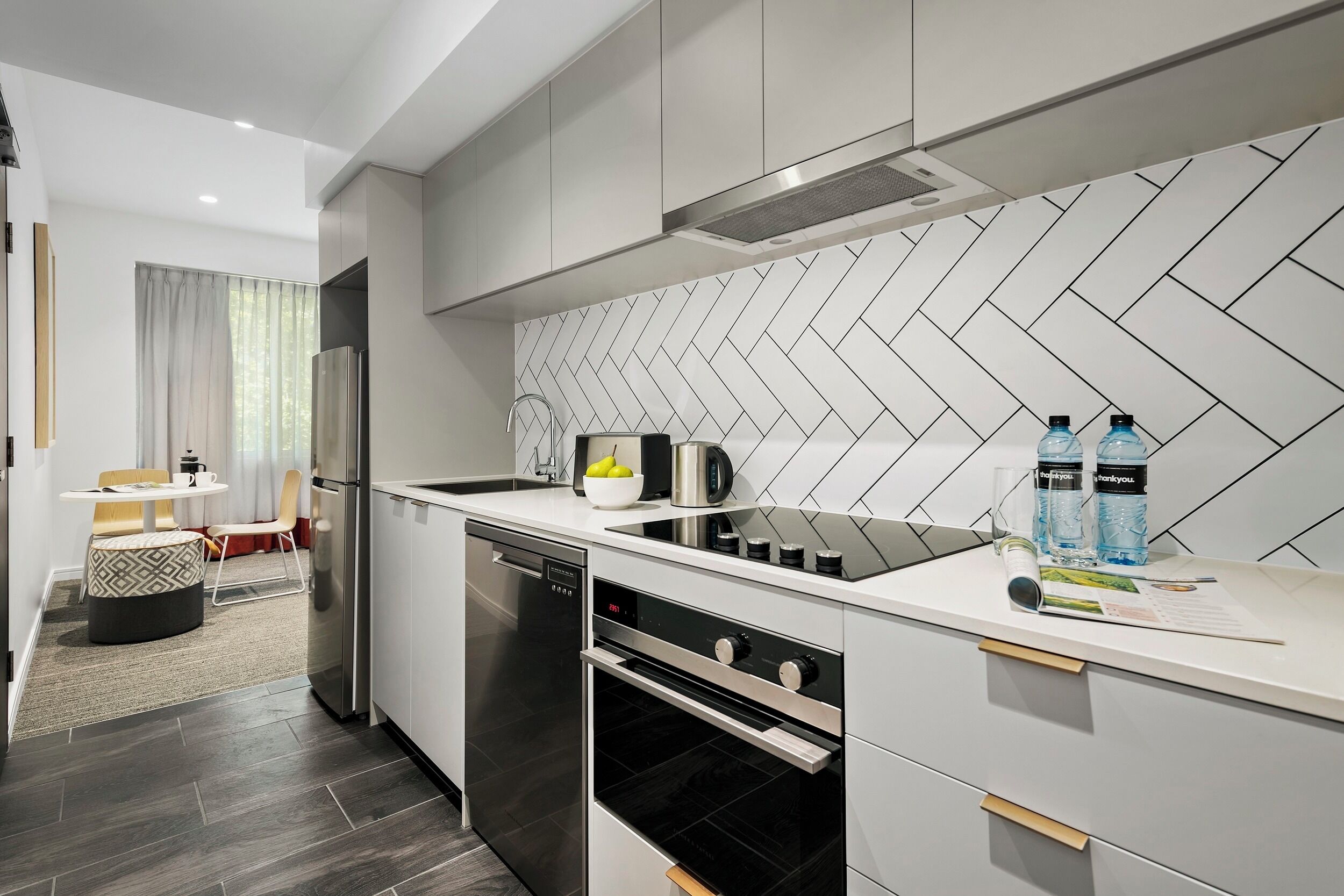 A modern kitchen with a dishwasher, oven, and a herringbone-patterned backsplash.