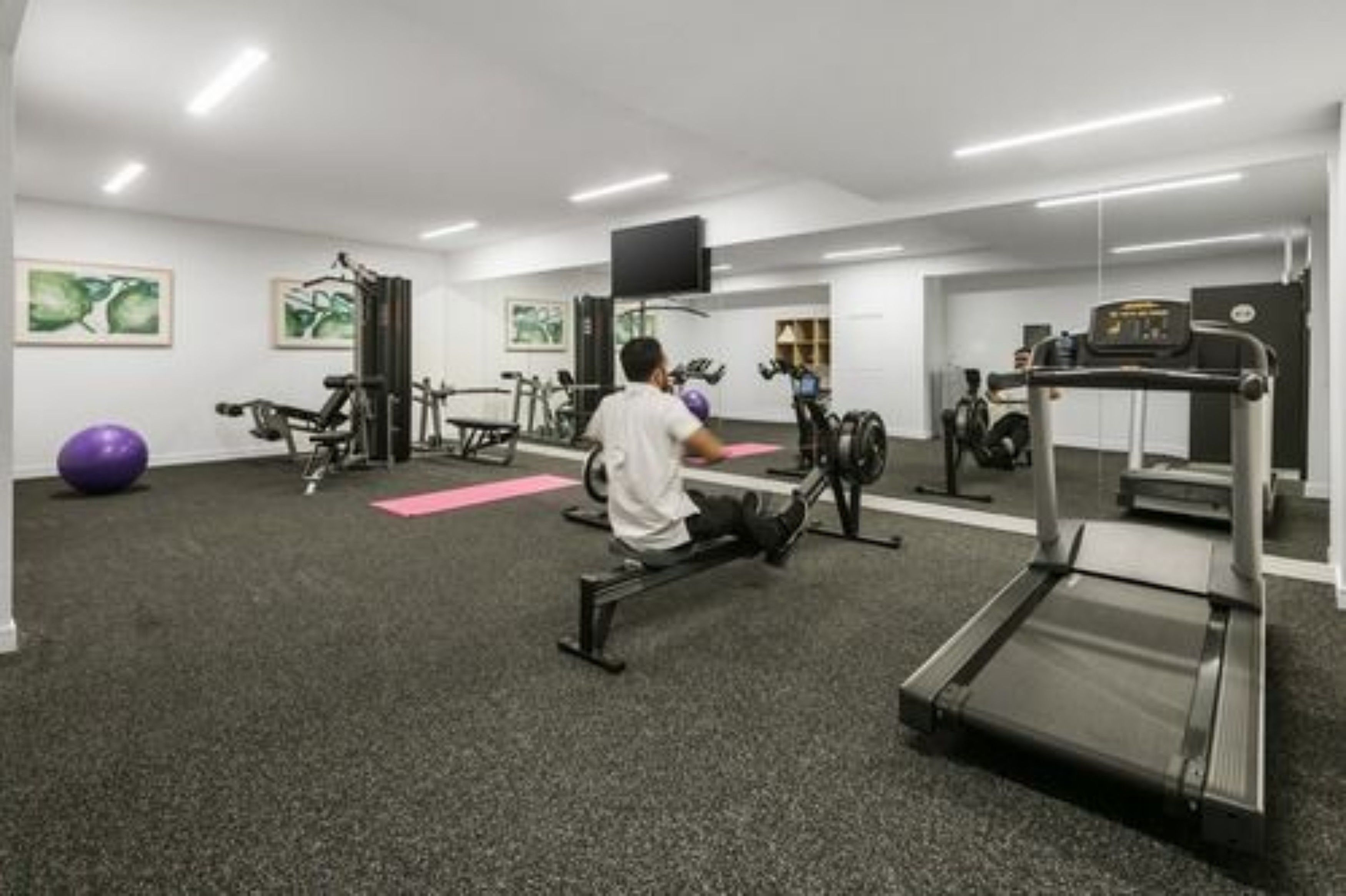 A gym with cardio equipment, weight machines, and a treadmill.