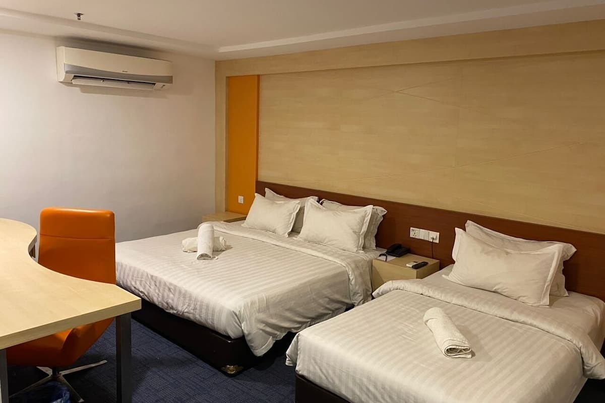 Une chambre d’hôtel avec deux lits simples, un bureau et une chaise orange.