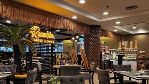 A restaurant interior with tables set for dining, a neon sign reading "Rumbella Coffee House," and a display of pastries. - De Palma Hotel Shah Alam (Shah Alam)