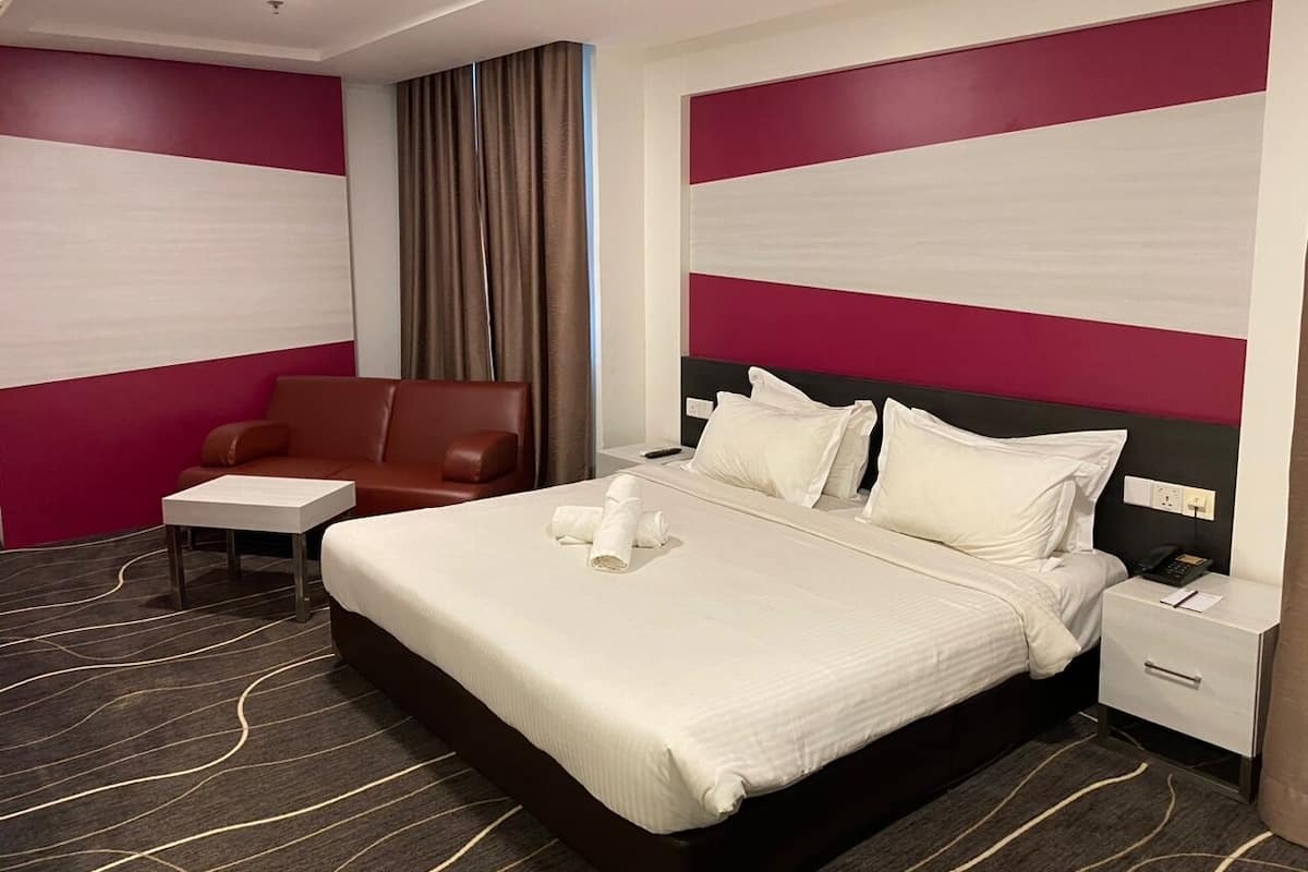 Une chambre d’hôtel avec un grand lit, une table de chevet, une chaise et un bureau.