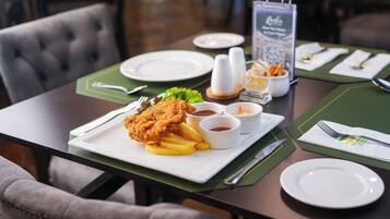 A dining table set with a plate of fried chicken and fries, condiments, and a menu stand.