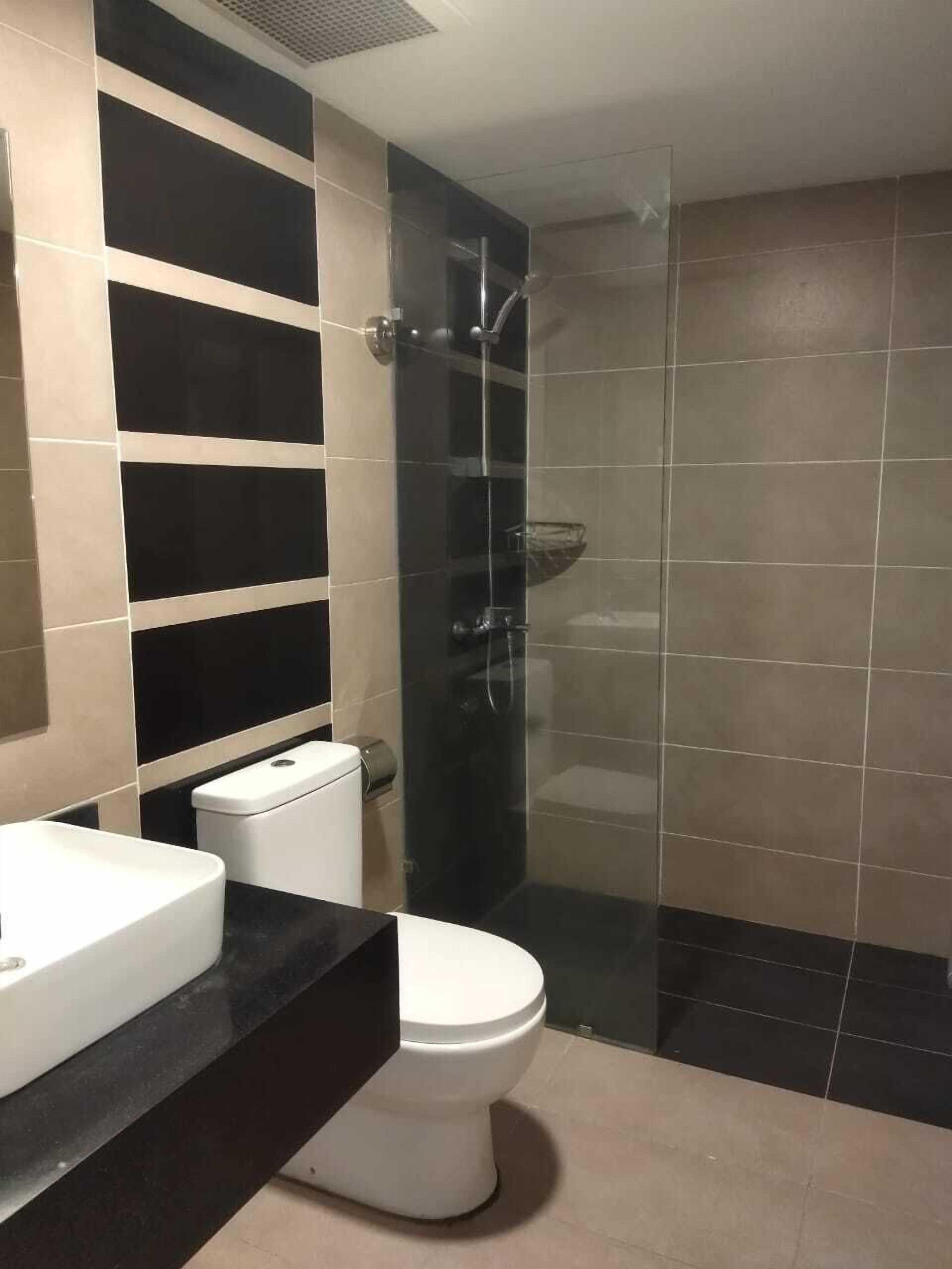 A modern bathroom with a toilet, sink, and glass-enclosed shower.