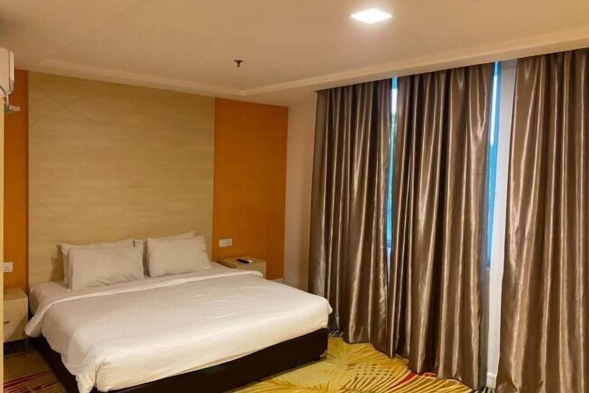 Une chambre d’hôtel avec un lit, des rideaux et une table de chevet.