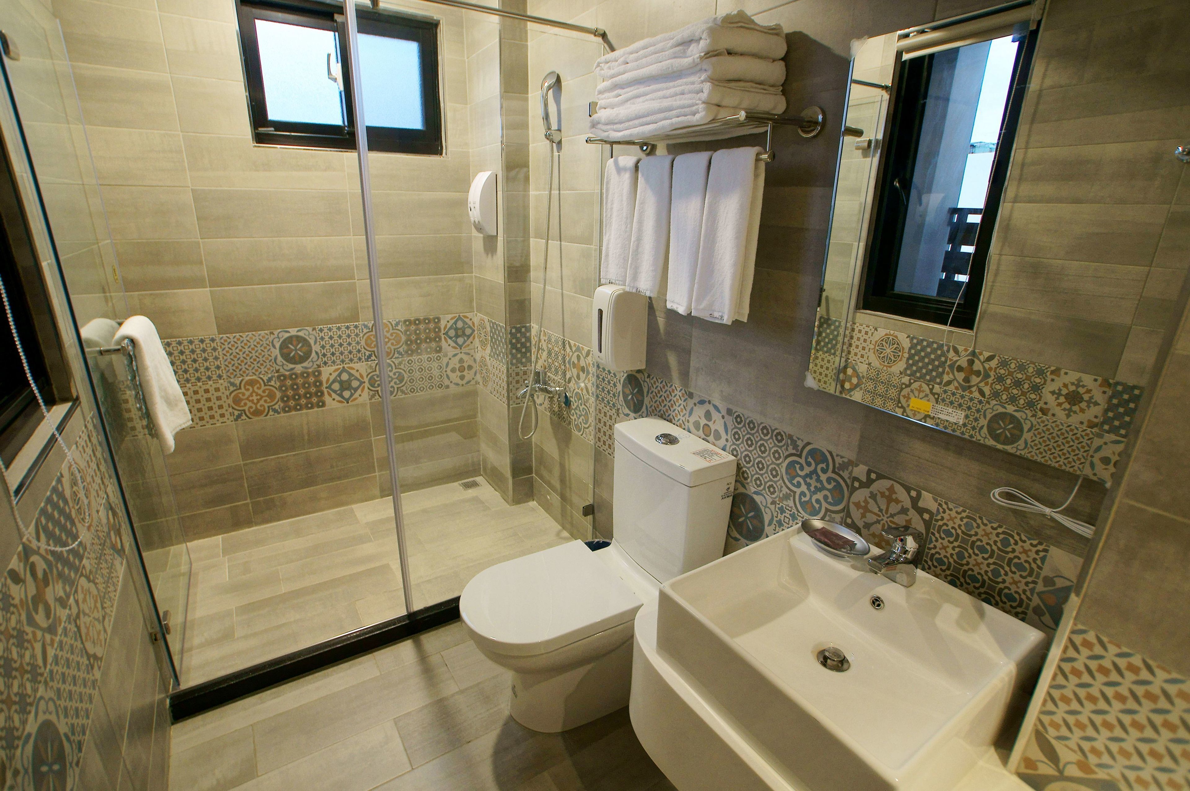 A bathroom with a glass shower enclosure, a toilet, and a sink.