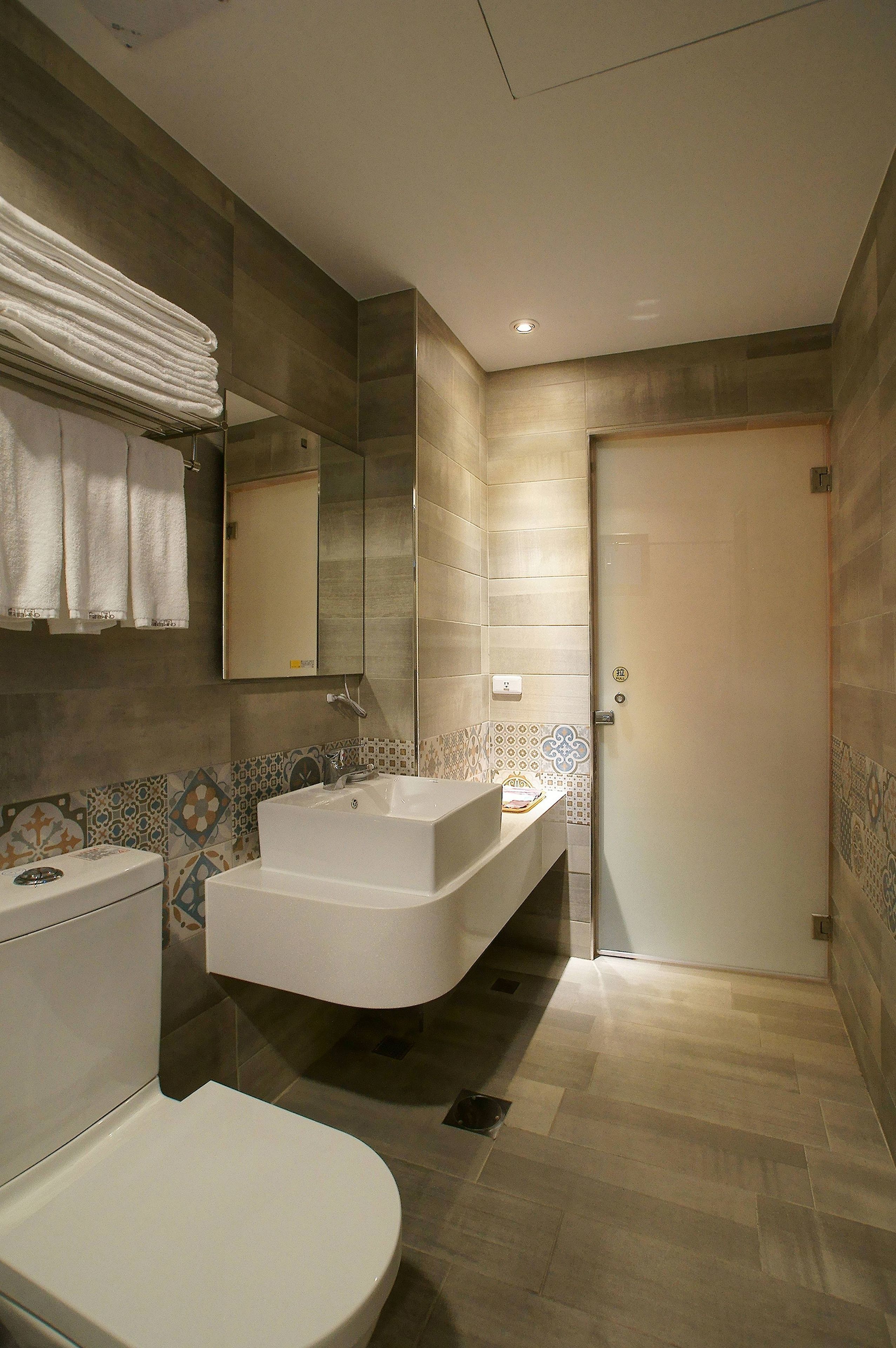 A modern bathroom with a toilet, a sink, and a mirror.