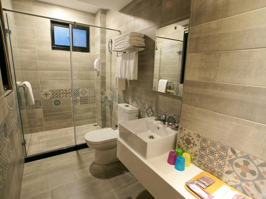 A modern bathroom with a glass-enclosed shower, a toilet, a bathtub, and a vanity with toiletries.