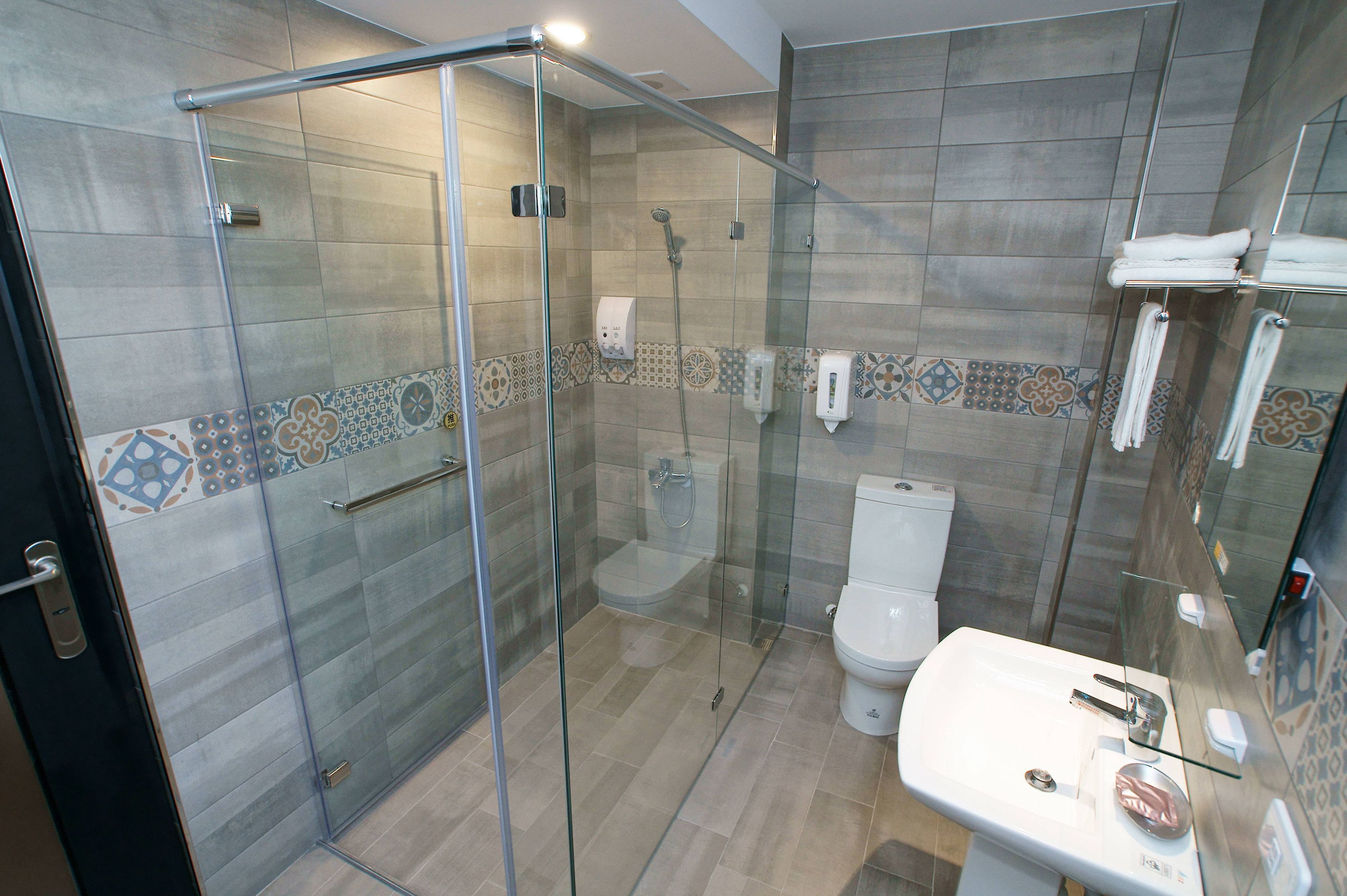 A modern bathroom with a glass-enclosed shower, a white sink, and a toilet.