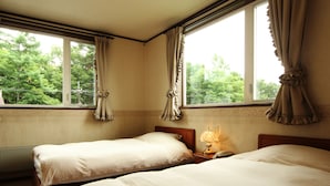 A hotel room with two beds, a nightstand with a lamp, and large windows with curtains.