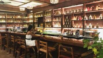A bar with wooden bar stools and shelves stocked with bottles.
