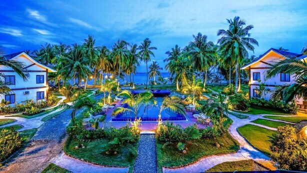 A resort with multiple buildings, a central pool, and palm trees. - Retreat Siargao Resort (General Luna)