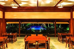 An indoor dining area with a view of a pool and garden at night. - Retreat Siargao Resort (General Luna)