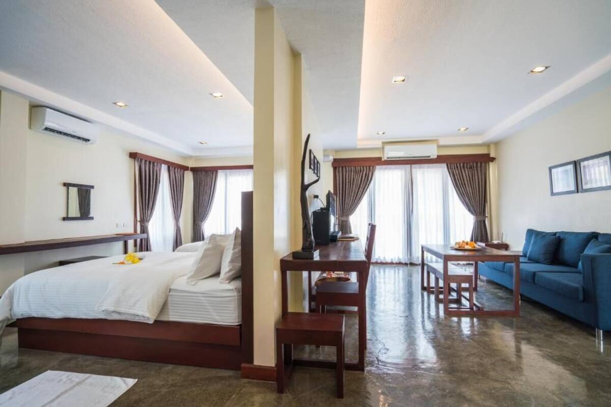 Ein Hotelzimmer mit Bett, Esstisch mit Stühlen, einer Couch und einem Fernseher.
