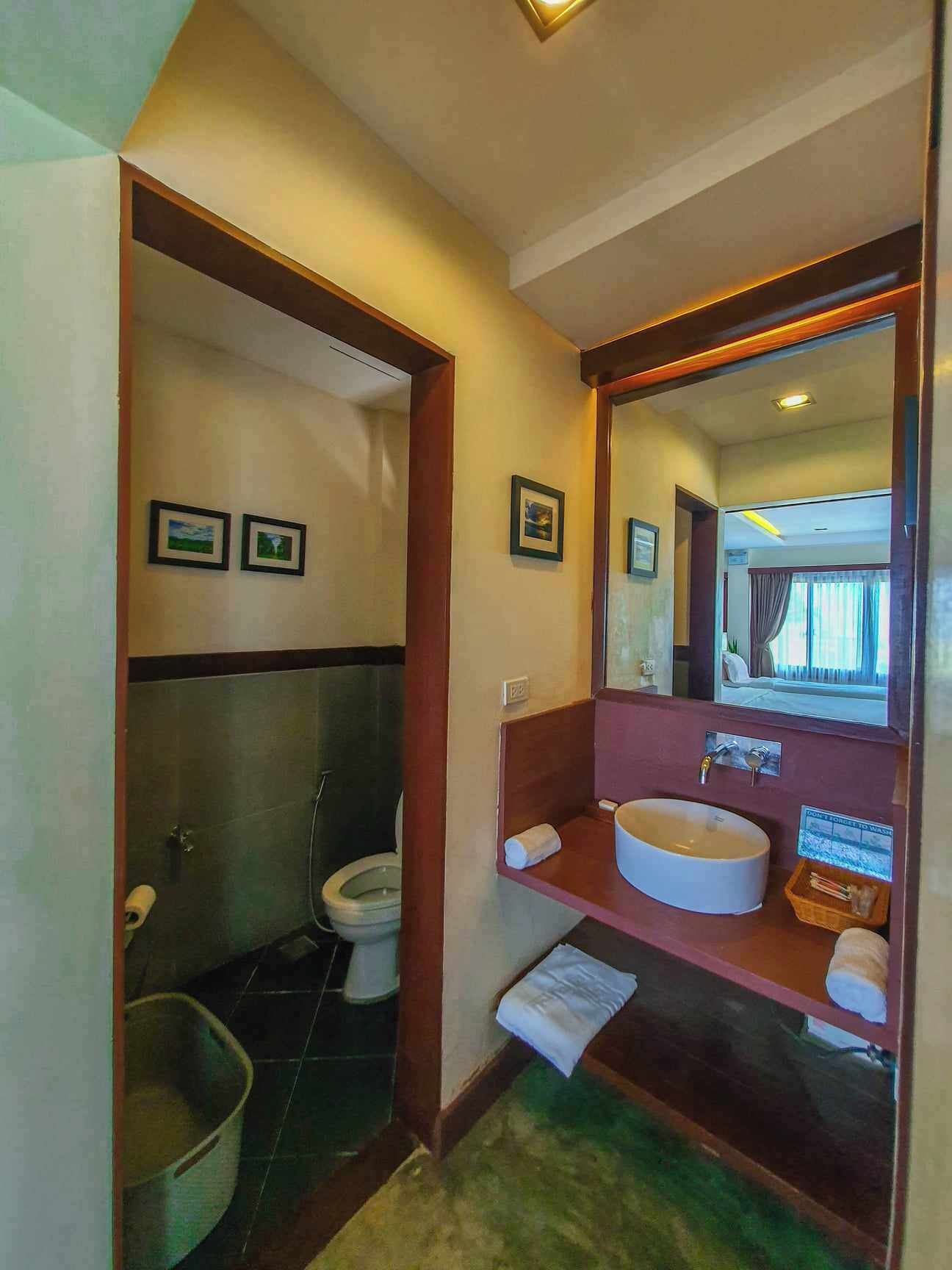 A compact bathroom with a toilet, sink, and a mirror.