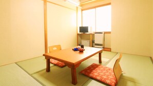 A traditional Japanese room with tatami flooring, a low wooden table, and a futon bed. - Kawatatsu (Nozawaonsen)
