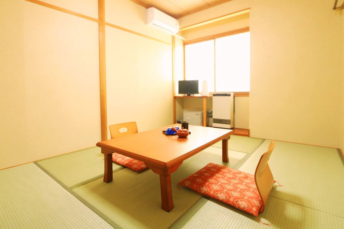 Ett traditionellt japanskt rum med tatamimattor på golvet, ett lågt träbord och en futonmadrass.