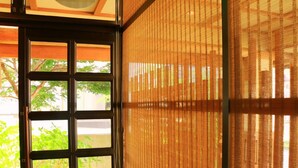 A room with a sliding door leading to an outdoor area, a window with a view of greenery, and a textured wall. - Kawatatsu (Nozawaonsen)