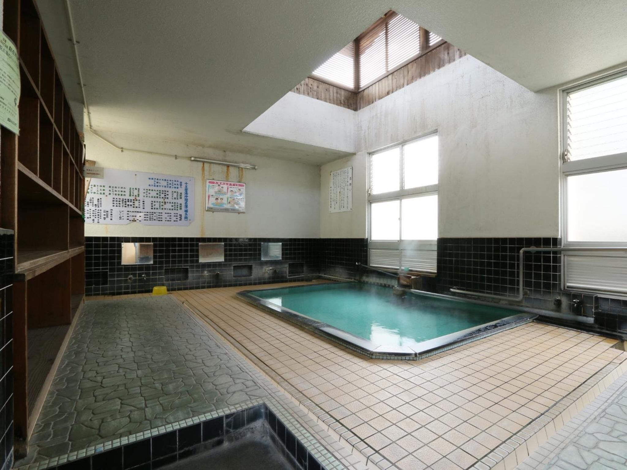 Une piscine avec un revêtement de sol en carrelage, une lucarne et une fenêtre.