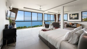 A modern hotel room with a large bed, a desk, and a view of the ocean. - Ban Nai Fan (Koh Samui)