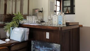 A bar area with a chalkboard menu listing drinks, a wooden counter, and a mirror above the bar. - Hostel Kura (Tokyo)