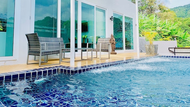 Zona de piscina con un patio de cristal, cubierta de baldosas y una estatua.