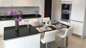 Una cocina moderna con armarios blancos, encimera negra y electrodomésticos de acero inoxidable.
