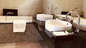 Un baño moderno con dos lavamanos, una bañera y una ducha.