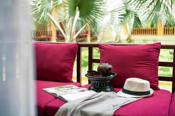 A red cushioned seating area with a book, a hat, and a decorative item on a table.