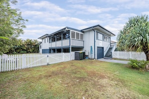 A two-story house with a balcony, a fenced yard, and a garage. - Very comfortable, pet friendly home located a short stroll from the beach... (South West Rocks)