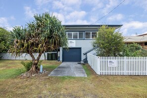 A residential property with a garage, a white picket fence, and a tree in the front yard. - Very comfortable, pet friendly home located a short stroll from the beach... (South West Rocks)