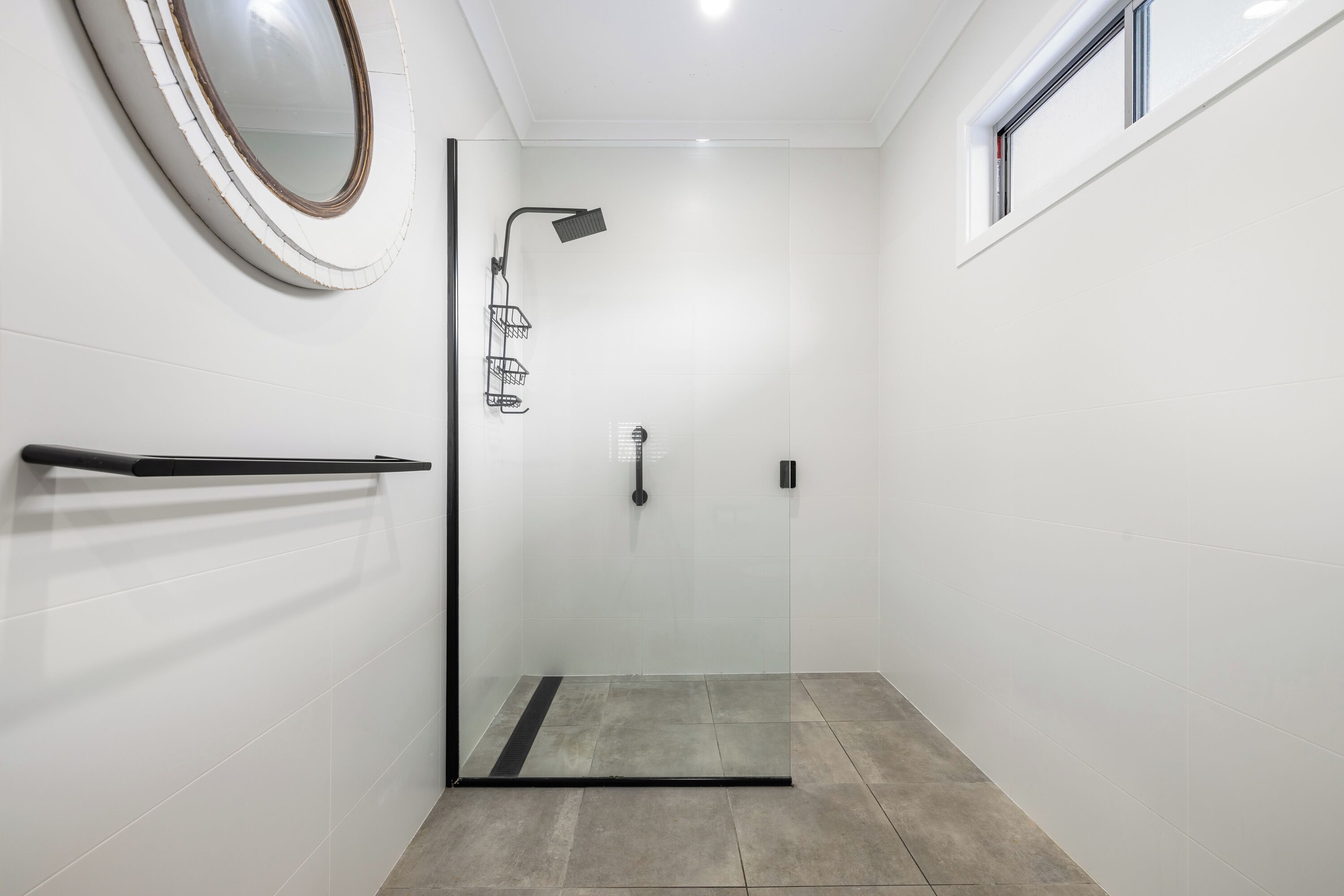Een moderne douche met een glazen deur, een handdoekhouder en een raam.