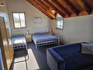 Ein Schlafzimmer mit zwei Betten, einem Schlafsofa und einem Fenster.