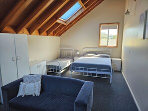 Une chambre de dortoir avec deux lits, un canapé, une armoire et une lucarne.