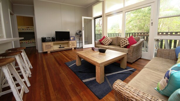 Un salón amplio con una mesa de centro de madera, un sofá y un televisor sobre un mueble de madera.