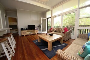 A spacious living area with a wooden coffee table, a sofa, and a TV on a wooden cabinet.